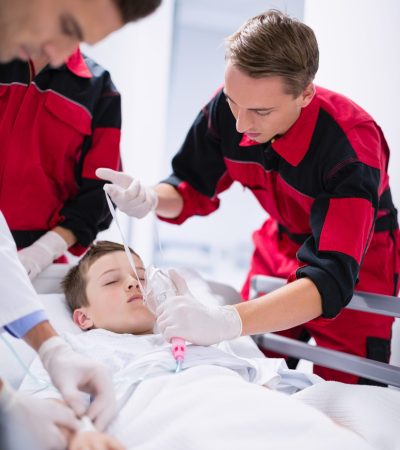 Doctors adjusting oxygen mask while rushing the patient in emergency room at hospital